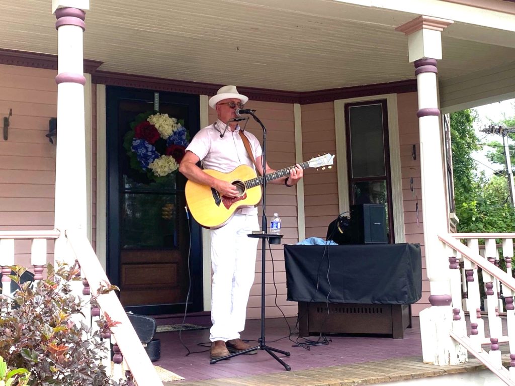 A gentleman plays guitar on a porch