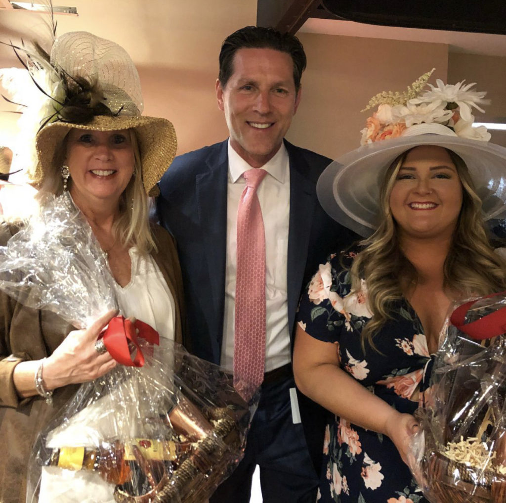 2 ladies in their derby outfits pose with a gentleman