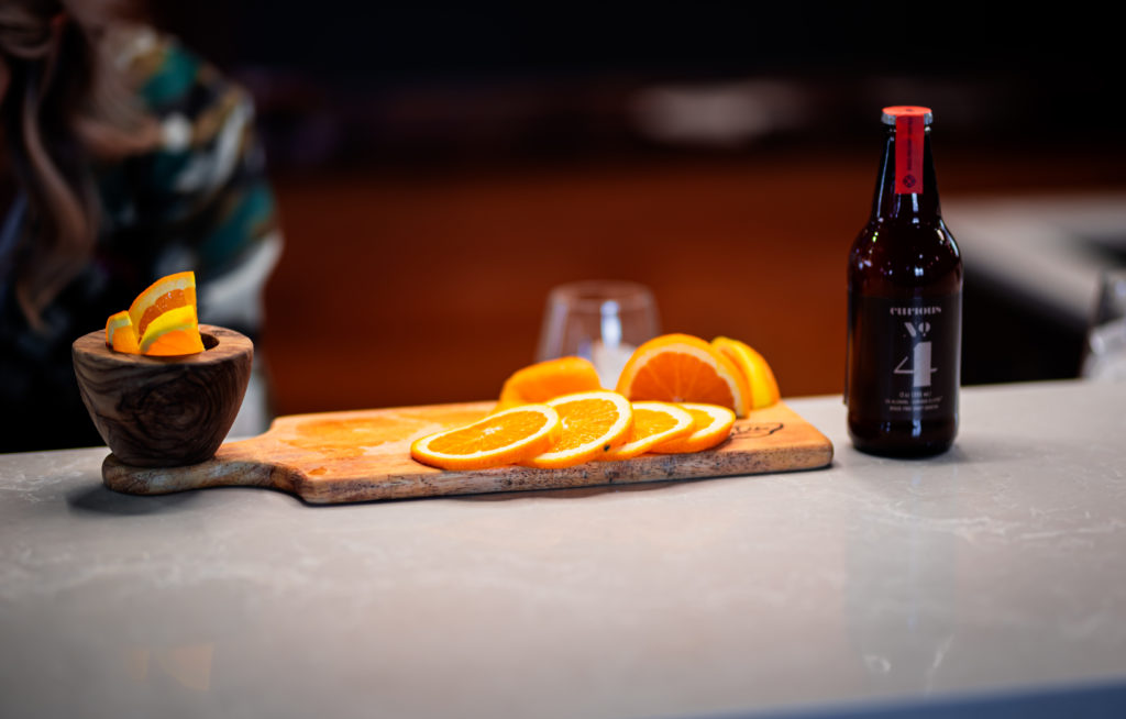 Curious Elixers' Curious No. 4 displayed with some sliced oranges