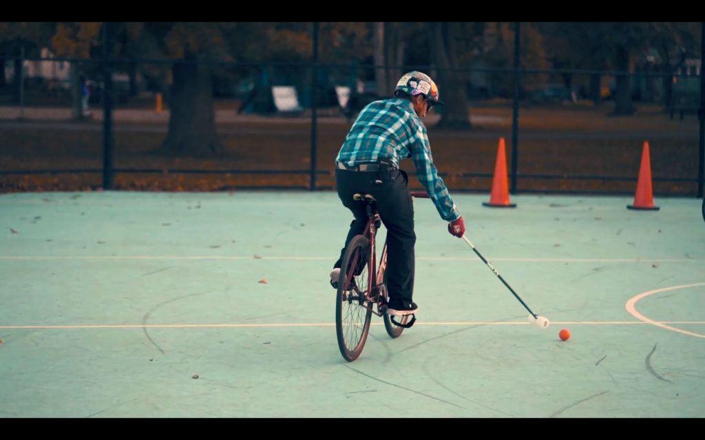 A bike polo player takes a shot at the goal