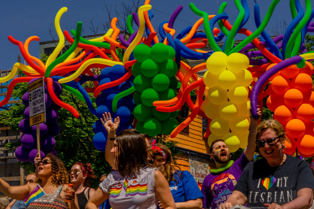 Parade participants show their pride under rainbow colored balloons