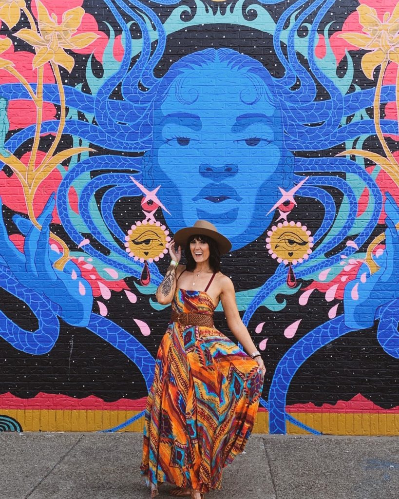 Photo of Nickel City Pretty in front of a colorful mural